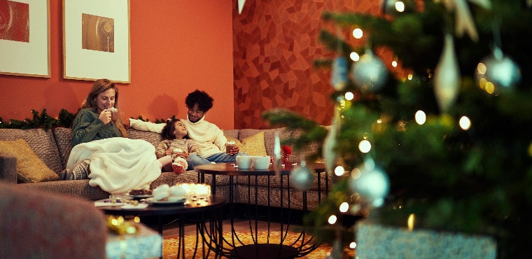 Family on the couch next to the Christmas tree
